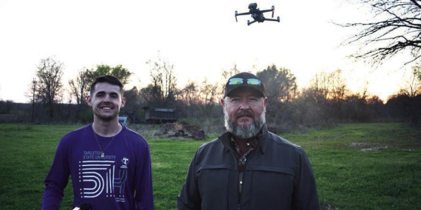 Logan Rice (lt) and his dad Lawrance Rice with their drone hovering in the background, about to scout a distant field for wild hogs. Courtesy Photo by Luke Clayton
