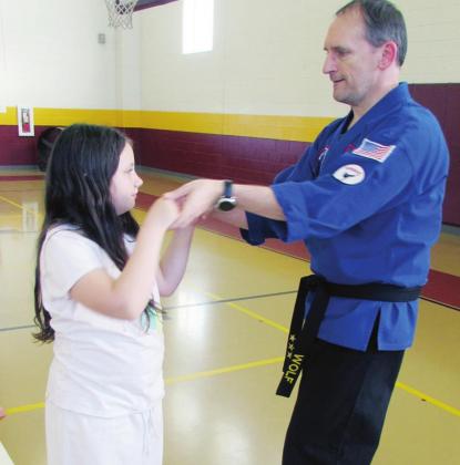 Andrew Wolf, who is a karate instructor with a black belt, is patiently showing his student how to make a particular move. Photo by Curtis Burton/ Fairfield Recorder