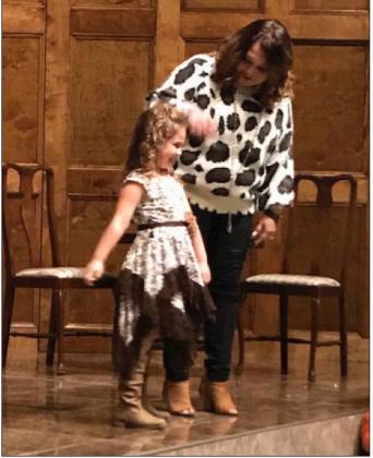 Parker Easter (left), helped along by mother Natalie Easter (right), gives a twirl to the audience as she displayed clothing from Peacocks and Ponies during the Freestone Cancer Support Group Fall Style Show and Dinner, held Oct. 22. Photo by Mary Cryer Awalt/Fairfield Recorder