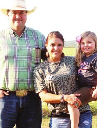 RIGHT: Cullen and Mandy Pickett of Pickett ProRodeo just outside of Fairfield stand in their backyard with their daughter, 3-year-old Masa Kay. The Picketts had the world champion bareback horse last year in 17-year-old Top Flight. Photo by Skip Leon/The Mexia News